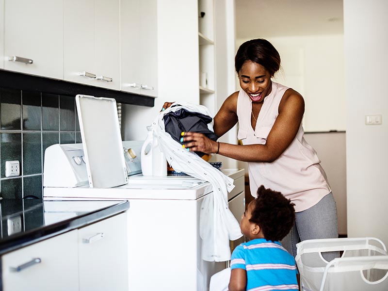 mother and son washing clothes in laundry room