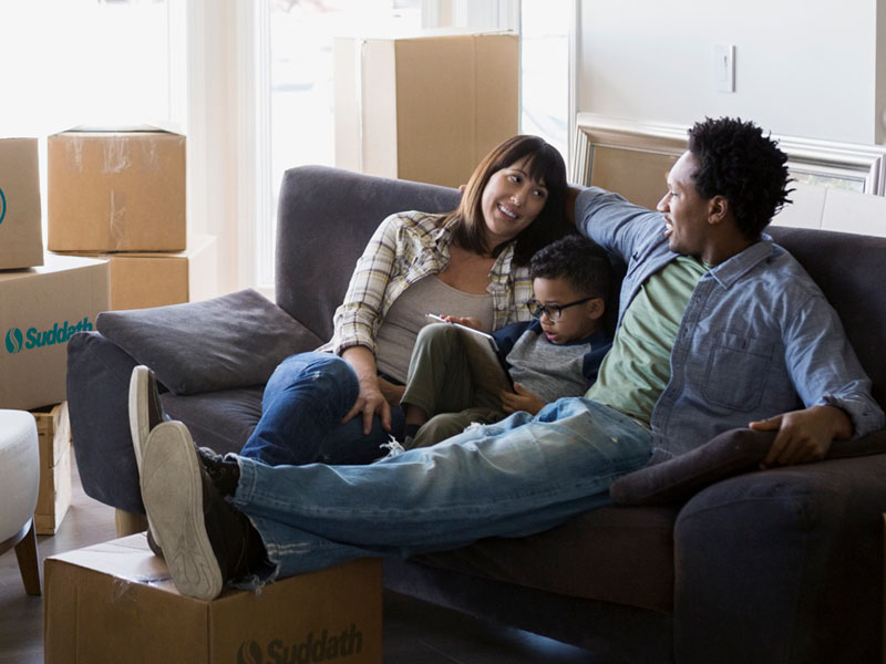 family sitting on sofa after home move